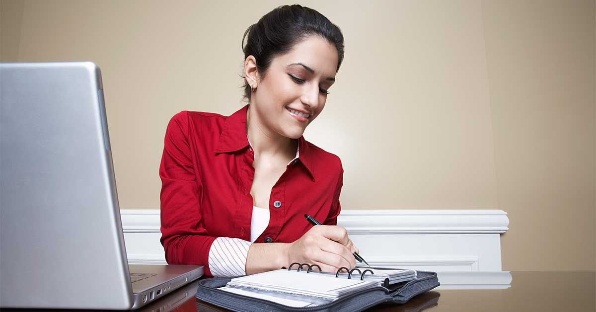 Business woman writing in a large diary