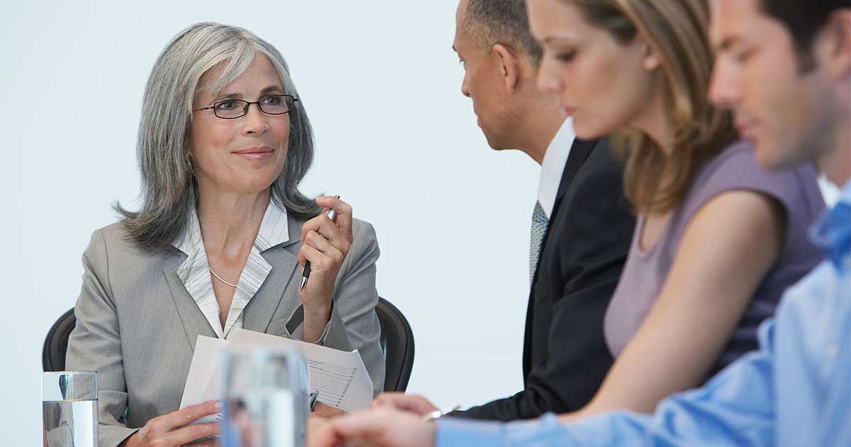 Mature grey-haired business woman in a meeting with three colleagues